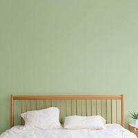Cozy bedroom with a wooden headboard and soft pillows against a light green wall photo