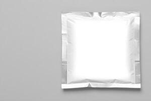 Blank silver foil sachet packaging on a grey background with copy space for branding photo