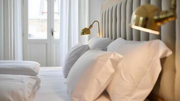 Comfortable hotel bed with crisp white linens and stylish brass bedside lamps photo