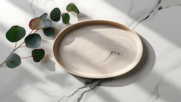 Minimalist arrangement of eucalyptus leaves on a marble surface with a decorative plate photo