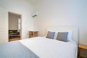 Modern minimalist bedroom with a comfortable bed and a view of a living area photo