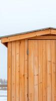 Rustic Wooden Shed Detail in Winter Close-up of Natural Timber Paneling and Roof Edge Against a Soft, Overcast Sky, Highlighting Architectural Simplicity and Warm Wood Tones photo