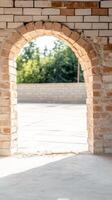 Sunlit brick archway framing a serene outdoor view, showcasing rustic architectural charm and the interplay of light and shadow on textured masonry. photo