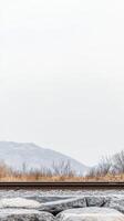 Scenic Railway Path Through Muted Winter Landscape Distant Mountains, Barren Vegetation, and Textured Rocks Under a Vast Sky photo