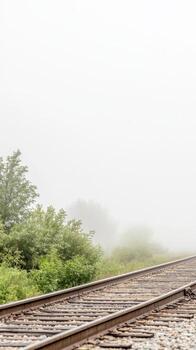 Atmospheric Train Tracks Disappearing into a Blanket of Morning Fog, Capturing the Serene Beauty of a Hazy, Mysterious Landscape. photo