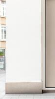 Clean, Modern Urban Building Facade with White Wall and Stone Base. Contemporary Architectural Detail on a City Street Pavement. photo