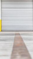 Industrial Roll-Up Door and Concrete Floor with Yellow Stripe Detail. Modern Warehouse Entrance Texture and Geometric Lines Background. photo