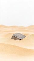 Minimalist desert landscape featuring a solitary dark rock nestled amidst the gentle undulations of golden sand, exuding tranquility and natural beauty. photo
