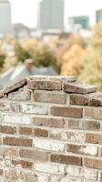 Weathered Brick Wall Texture with Blurred Urban Cityscape Background, Rustic Architectural Detail and Rooftop View, Ideal for Design and Decor photo