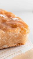Exquisite Caramel Glazed Pastry A Close-Up View of Golden, Flaky Perfection on a Rustic Wooden Board, Highlighting Delicious Texture and Sweetness photo