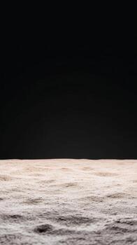 Subtle textured surface, evoking a lunar landscape or fine desert sand, rising from a deep, dramatic black void, creating a serene, abstract backdrop. photo