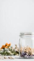 Elegant still life of dried floral elements in a clear glass jar, set against a pristine white backdrop. Perfect for natural decor, herbal concepts, and serene compositions. photo