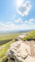 Breathtaking Mountain View Expansive Green Plains and Sunny Blue Sky from a Scenic Cliff Overlook, Capturing Nature's Grandeur and Serenity photo