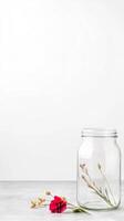 Elegant still life with a vibrant red flower and dried botanical elements beside a clear glass jar on a minimalist white and grey backdrop, evoking serene natural beauty. photo