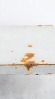 Close-up of a weathered white metal surface with prominent orange and brown rust spots, creating a textured, grunge industrial background perfect for design elements photo