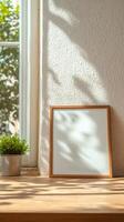 Blank Wooden Frame Mockup with Potted Plant on Sunny Window Sill. Cozy Home Interior Decor with Natural Light and Leaf Shadows photo