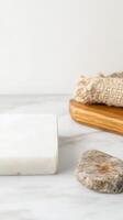 Natural Spa Essentials Serene Marble Surface with Organic Soap, Smooth Stone, and Textured Loofah on a Wooden Tray for Wellness and Self-Care. photo