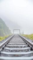 Enigmatic Railway Tracks Disappearing into Dense Fog, Leading to a Mysterious Bridge. A Serene Landscape Journey on a Misty Overcast Day. photo