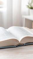 Open book resting on a light wooden table, its pages filled with text, bathed in soft natural light, symbolizing knowledge, quiet study, and the joy of reading. photo