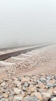 Mysterious train tracks disappear into a dense, ethereal fog, evoking a sense of tranquil solitude and an unknown journey ahead. A captivating, atmospheric landscape. photo