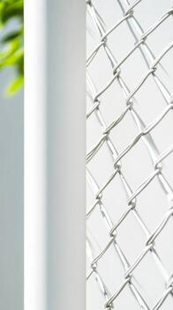 Close-up of a pristine white chain-link fence with a sturdy pole, casting subtle shadows under bright daylight, highlighting geometric patterns. photo