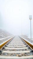 Enigmatic Railway Tracks Vanishing into Dense Winter Fog, a Solitary Path Through a Chilly, Serene Landscape with Gleaming Golden Rails and a Distant Signal. photo