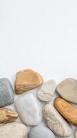 A serene composition of smooth, natural river stones and pebbles, showcasing earthy textures and calming hues on a pristine white background. photo
