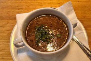 Hearty Mushroom Soup in White Bowl on Wooden Table with Garnish photo