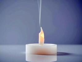 A burning candle is lit in a small white tea light photo