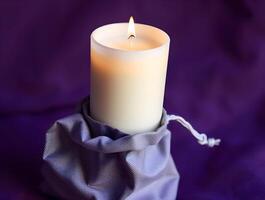 A white candle is sitting in a bag on a purple background photo