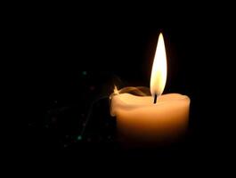 A lit candle is shown on a black background photo