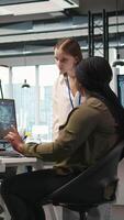 Vertical Smiling startup manager teaching junior dev how to use machine learning tech. Happy african american team leader showing intern in office how to use AI predictive models, camera A video