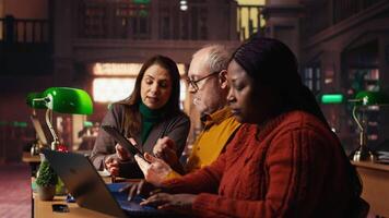 Focused students taking notes from academic library resources and reviewing archived materials in a study area, showing the dedication of mature education and knowledge building. Camera B. video