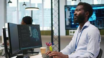 computer wetenschapper gebruik makend van ai Aan computer naar optimaliseren prestatie en voorspelling problemen. Afrikaanse Amerikaans arbeider in kantoor opleiding machine aan het leren modellen gebruik makend van pc, camera een video