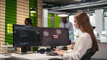 kvinna ingenjör i börja kontor kämpar till fixera kritisk fel varning dyka upp. internera håller på med underhåll på dator glitches medan kodning i programvara utveckling byrå, kamera en video