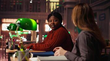 mogna kvinna läsning och använder sig av stryknings penna på tryckt kurser i en offentlig bibliotek under en grön lampa, fokuserade på studerar dokument. memorerande Viktig lektion idéer. kamera b. video