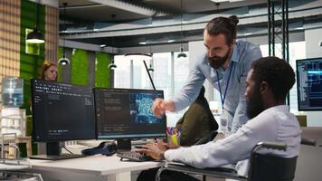 Startup engineer and colleague with paraplegia brainstorming, working with machine learning tech. Man in wheelchair and coworker in office transforming data into AI predictive models, camera A video