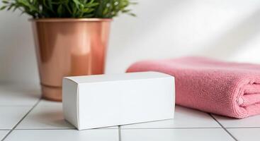 Clean white bar of soap next to a pink towel and plant in a bathroom setting photo