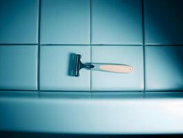 A razor is sitting on top of a blue tiled wall photo