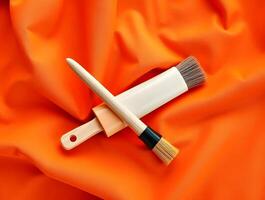 A brush and a paintbrush laying on an orange fabric photo
