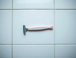 A razor is sitting on a tiled wall photo