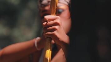 A Javanese archer with theatrical makeup and a batik headwrap holds a golden bow, hiding part of his face. The shot is mysterious and powerful, focusing on the character from Indonesian folklore. video
