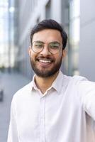 Phone webcam view, businessman looking into camera, talking to colleagues smiling contentedly, man in shirt walking outside office building photo