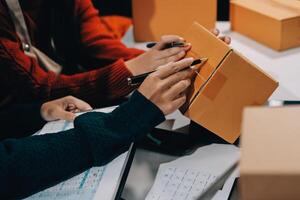 Two people are working on a computer with a box photo