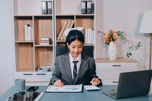 Asian business woman working at desk with laptop and papers photo