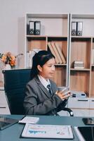 A young woman in a business suit sitting at a desk with a cup of coffee photo