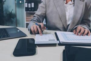A woman in a suit is working on a calculator photo