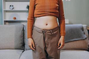 A woman in a brown pantsuit standing in front of a couch photo
