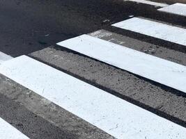 Freshly painted pedestrian crossing lines create a clear path for walkers in a lively urban setting during daylight hours photo