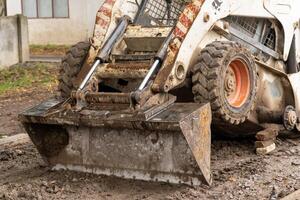 A skid steer is prepping the ground at a construction site nestled in nature, signaling ongoing development photo